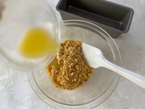 砕いたクッキーに溶かしバターを回しかける様子
