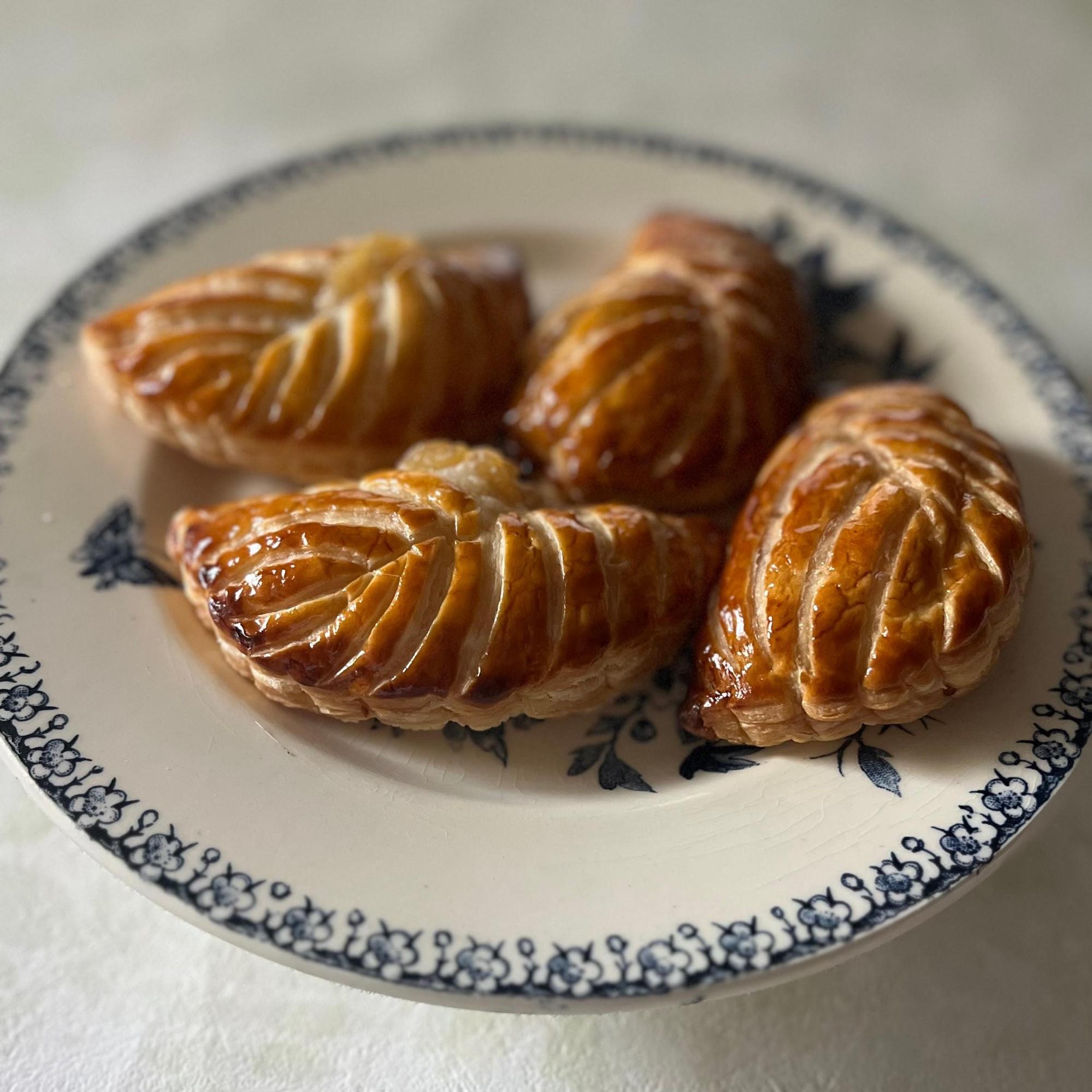 お皿にフランスの伝統菓子「ショーソン・オ・ポム」が4つ乗っている写真