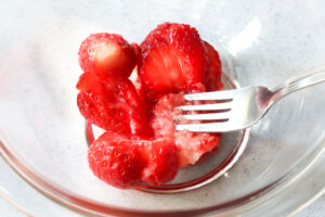 ボウルに入れたイチゴをフォークで潰す様子