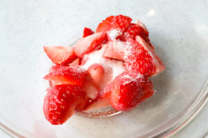 ボウルに縦1/4カットにされたイチゴと砂糖入っている写真