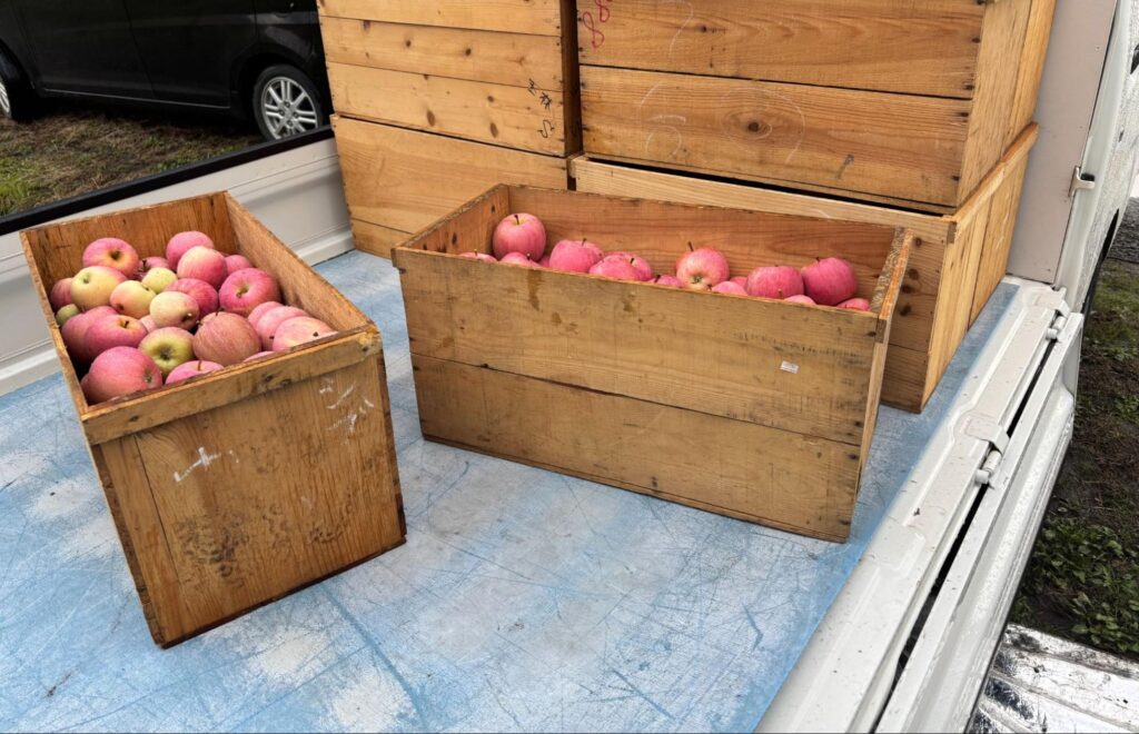 軽トラックの荷台にりんごがたくさん入った木箱が積まれている写真