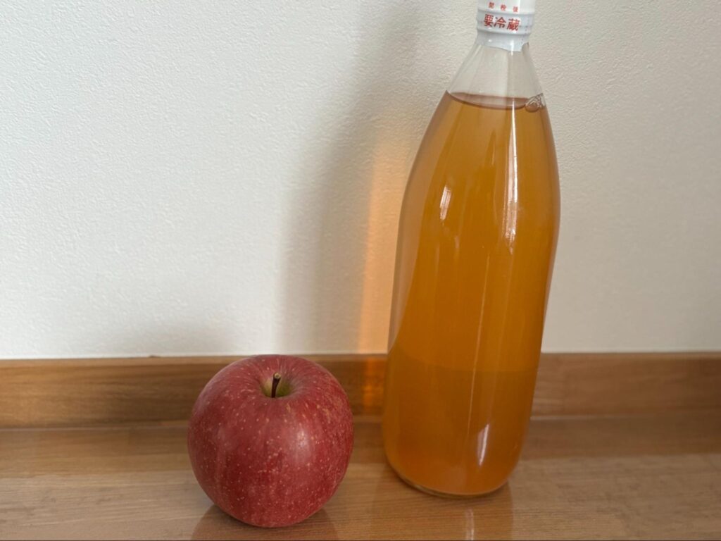 りんごとボトルに入ったりんごジュースが並んでいる写真