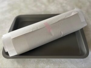 紙を巻いてテープで止めた状態のロールケーキ