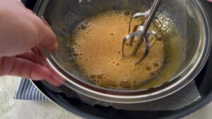 ボウルに入れた材料をハンドミキサーで混ぜながら湯せんする様子