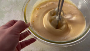 垂直にしたハンドミキサーで卵を泡立てる様子