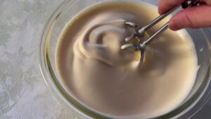 手ハンドミキサーのハネを持ち、卵液全体をぐるぐるとまぜる様子