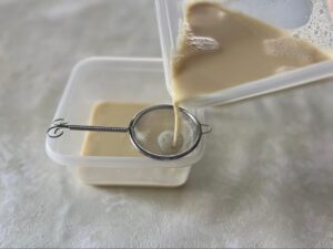 豆乳を茶漉しで漉す様子