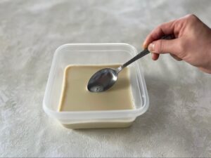 豆乳の表面に浮いた気泡をスプーンですくう様子