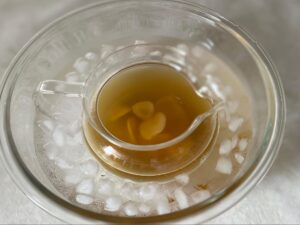 生姜シロップの入った容器を氷水で冷やす様子