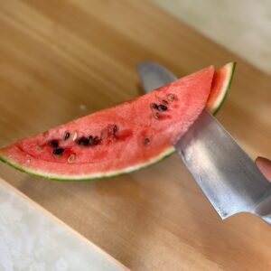くし切りにしたスイカの皮を包丁で外す様子