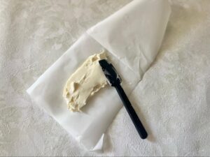 クリームチーズをゴムベラでクッキングシートに広げる様子