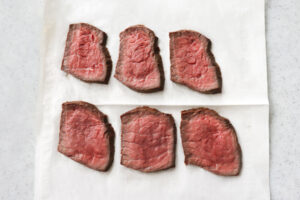 キッチンペーパーに並んだスライス肉の写真