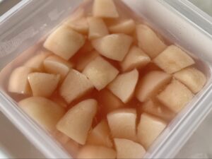タッパーにコンポート液と一口サイズの桃をいれた写真